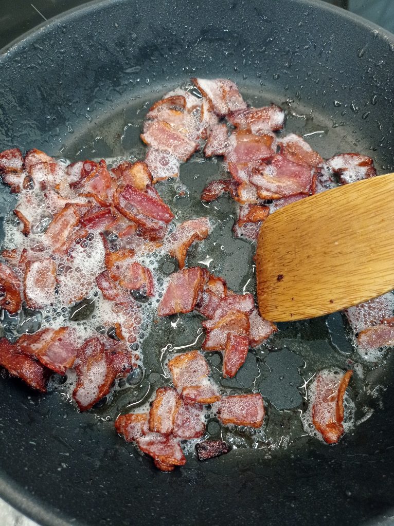 trozos de bacon cocinando en una sartén