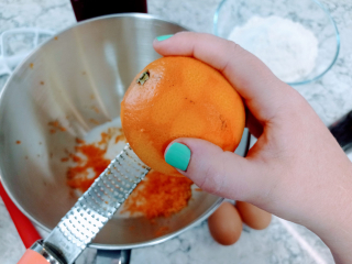 rallando una naranja en el tazón de ingredientes de bizcocho de naranja y chocolate