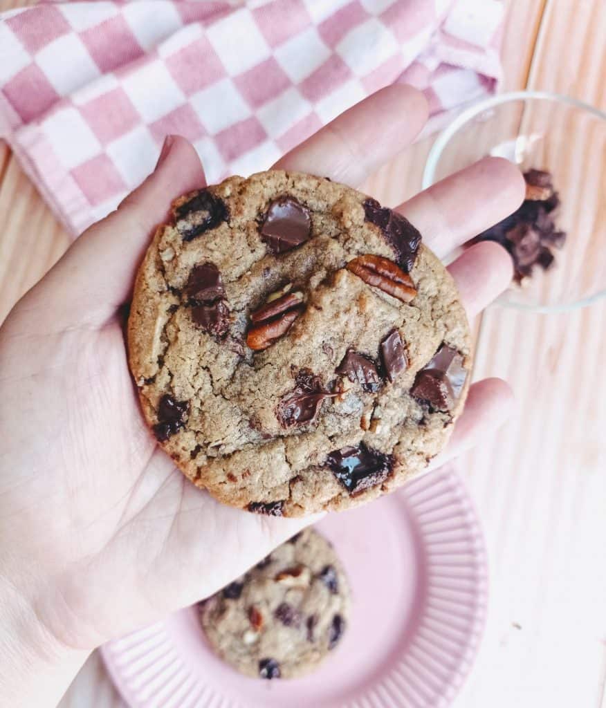una galleta de chocolate americano con nueces en una mano