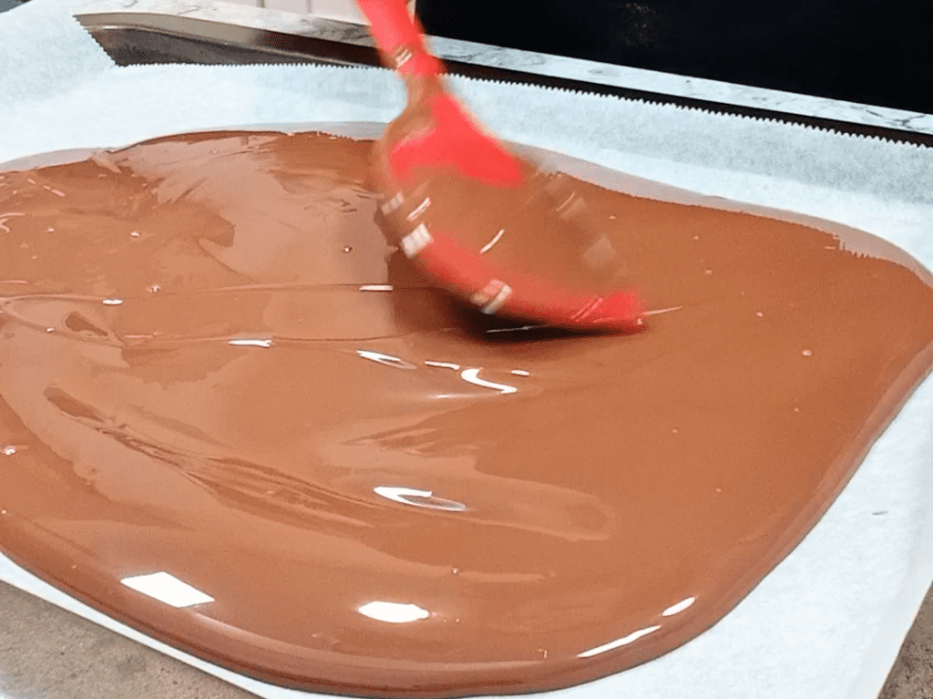 esparciendo el chocolate derretido en la bandeja forrada