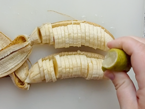 exprimiendo el jugo de limón encima de las rodajas de plátano